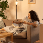 Frau liegt auf dem Sofa und liest in einem Buch.